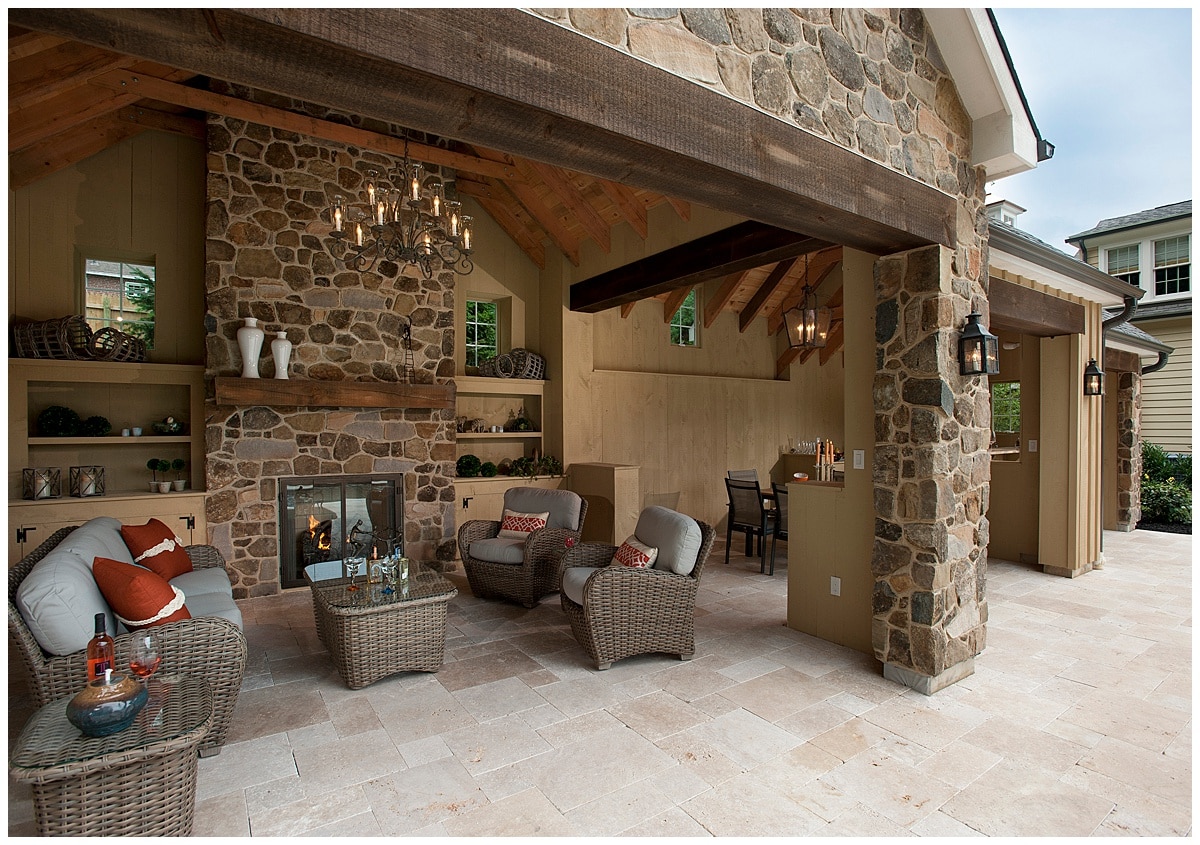 An outdoor patio space with a stone fireplace and rattan furniture.
