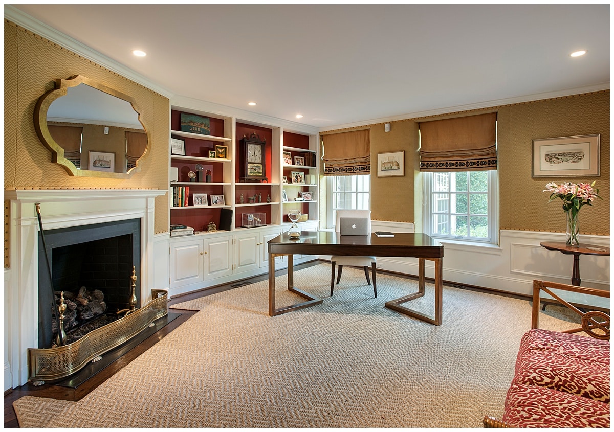 A home office with built-in library wall and a desk placed in the corner.