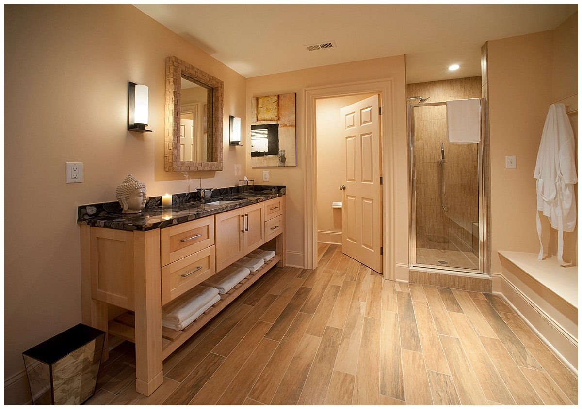 Spacious bathroom with private toilet room, standing shower, and large wooden sink with stone countertop.