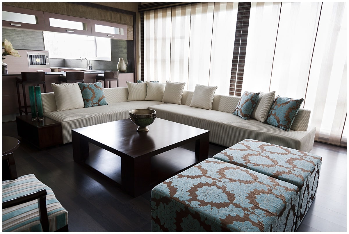 Living room with sectional couch that has blue and brown upholstered seating, surrounding a coffee table