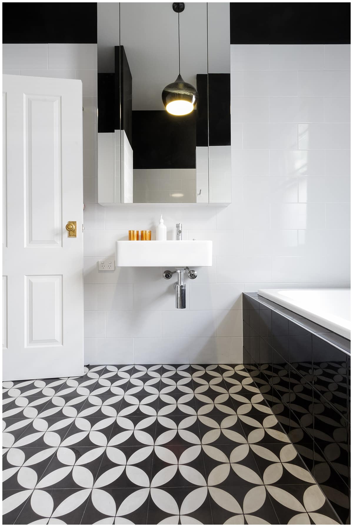 Bathroom with black and white tile, black tub, and black wall accent