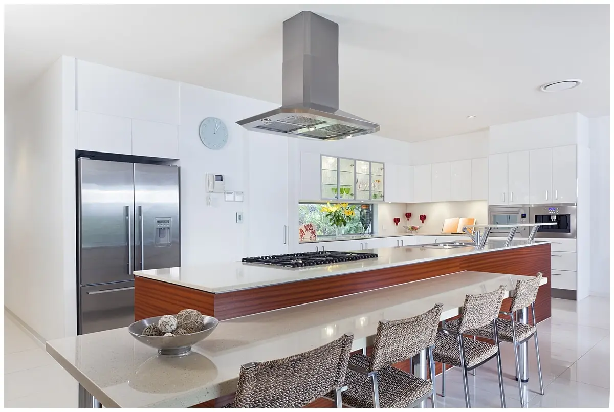 Kitchen island with high-end hood vent over electric stove area.